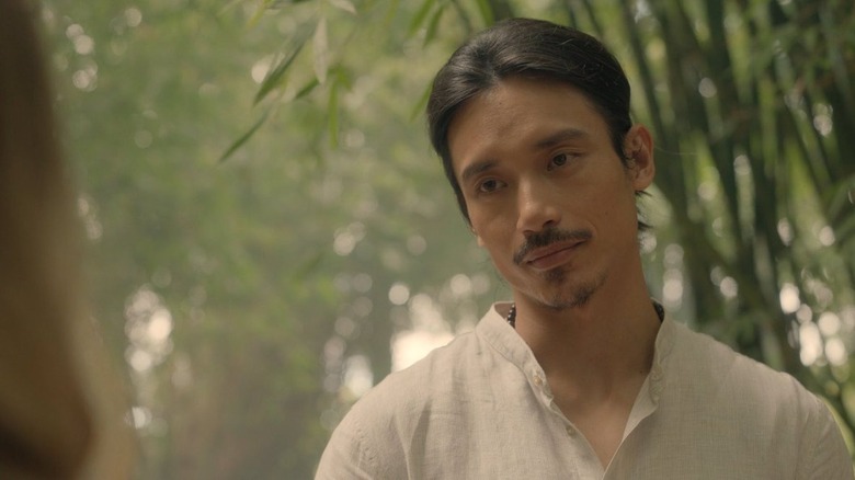 Manny Jacinto as Yao in a forest wearing a white shirt in Nine Perfect Strangers