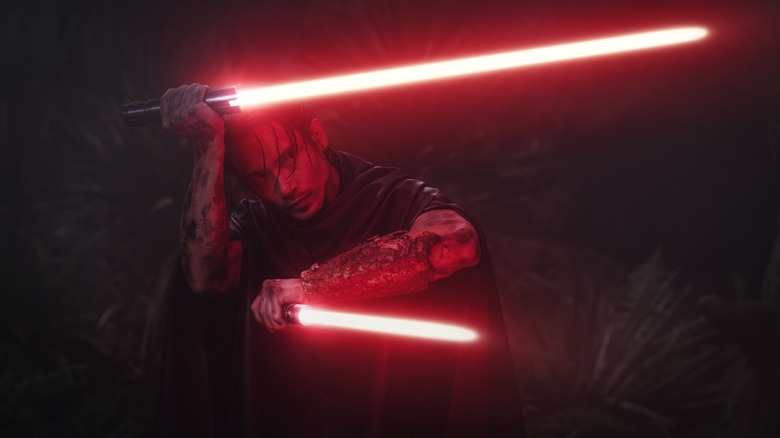 Manny Jacinto as Qimir wielding two red lightsabers